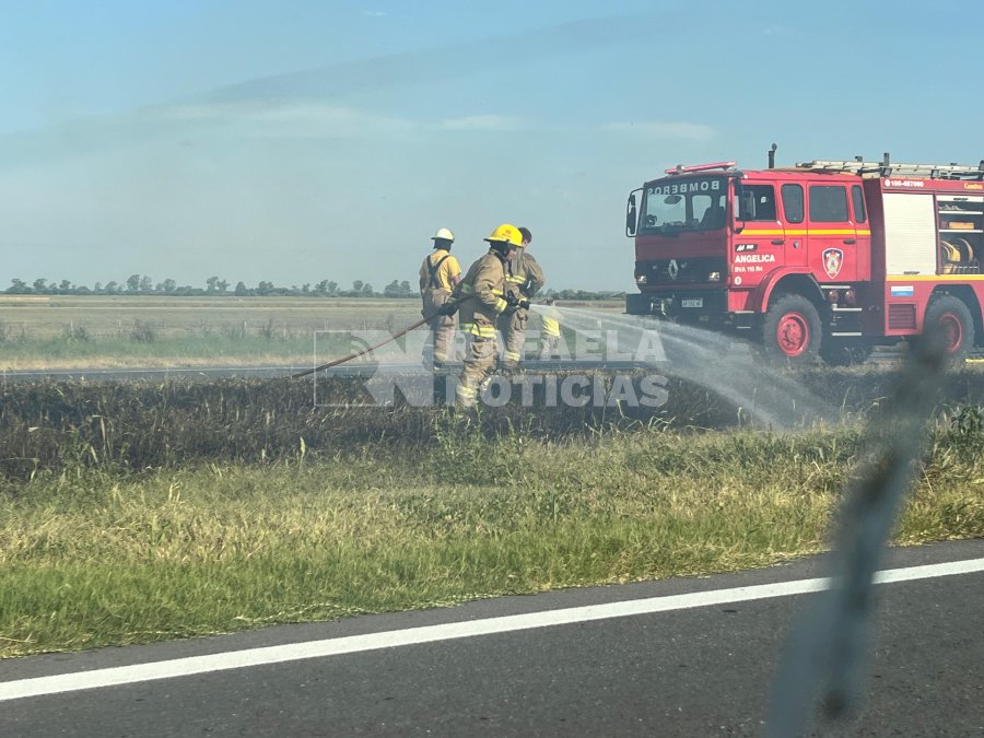 Bomberos de Ang&eacute;lica apagando pastizales tras el siniestro en el Peugeot 408.