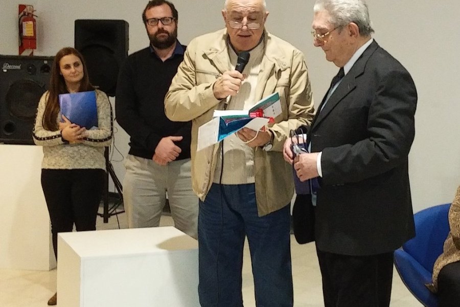 Fortunato Nari, de pie y de traje oscuro, recibiendo una distinci&oacute;n en el Viejo Mercado.